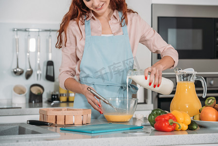 面糊摄影照片_妇女在碗中倒入牛奶准备面糊的裁剪图像