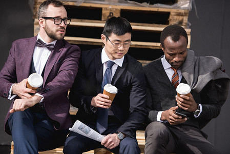 年轻的多民族商人在正装坐在喝咖啡休息时间在户外，业务团队会议