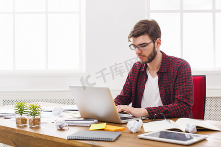 忙着呢摄影照片_年轻的商人与笔记本电脑在现代白色办公室工作