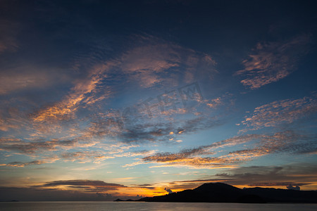 红色浪花背景摄影照片_多云的天空下宁静的日落海景风景