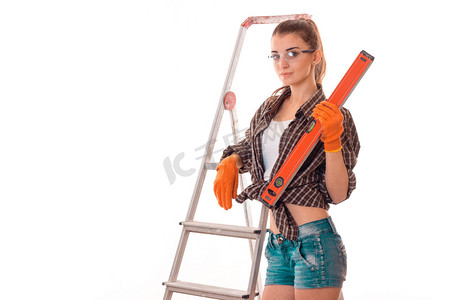 有吸引力的年轻女孩在短期短裤和衬衫站在附近一个小梯子和他手里拿着一种测量装置