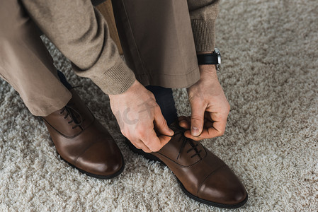 Close-up view of man tying shoelaces of his leather shoes