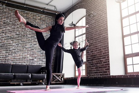 母亲和小女儿做站立分开的腿舒展锻炼保持平衡