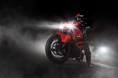超级摩托车司机夜间与烟雾周围