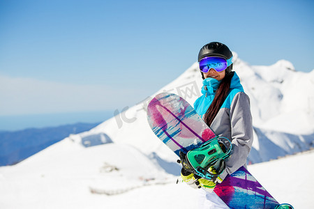 妇女徒步滑雪头盔的相片在雪山背景上滑雪板