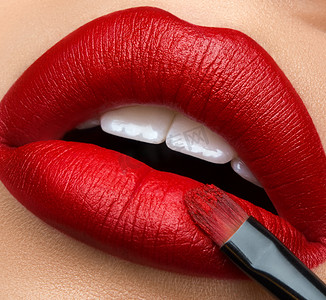 宏观和特写创意化妆主题: 美丽的女性嘴唇与红色口红和刷子