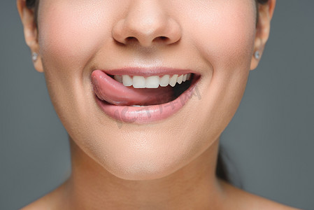 牙齿白化摄影照片_白色牙齿贴舌的微笑妇女的部分看法灰色隔离