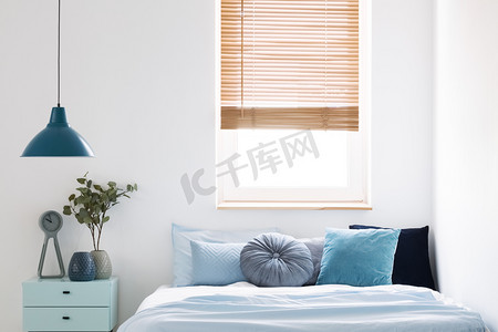 灯以上蓝色橱柜与植物旁边的床在简单的卧室内部与窗口。真实照片