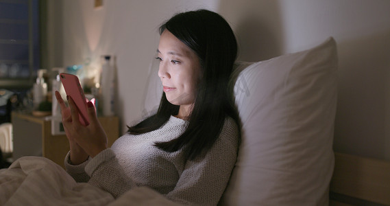 晚上看手机摄影照片_晚上在家使用移动电话的妇女 