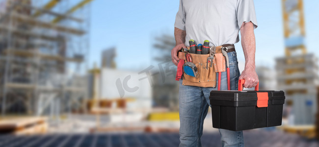 Building worker with tool belt on a construction site background