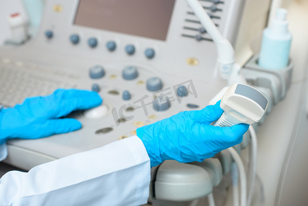 超声扫描仪在手套工作中的产科妇科医生的裁剪照片