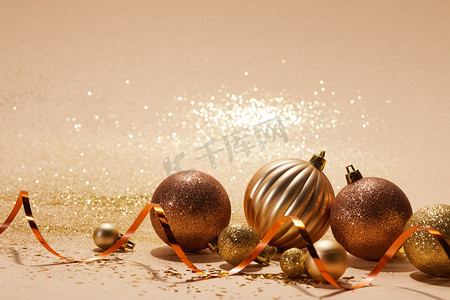 新年会议背景摄影照片_米色桌面上闪闪发亮的圣诞球和波浪丝带