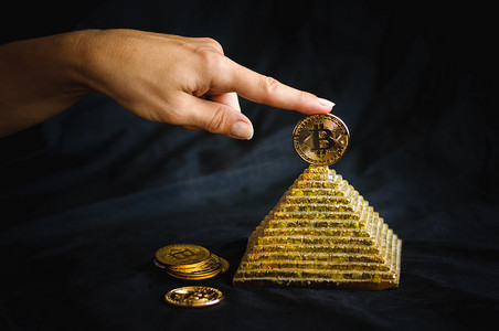 手指在金字塔顶部持有金币比特币