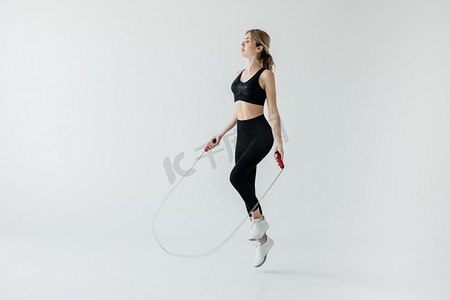 运动风格摄影照片_年轻运动女子跳绳的灰色隔离