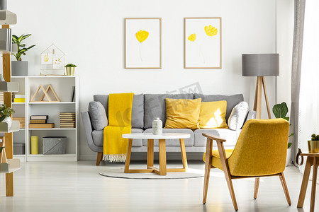 黄色木扶手椅和桌子在客厅内部与海报上面灰色沙发真实照片