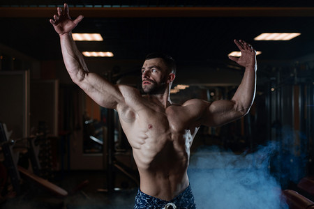 一个肌肉发达的野蛮运动男子在健身房里摆姿势, 炫耀他的肌肉。健康生活方式的概念