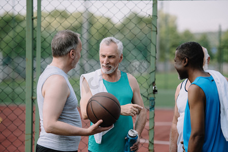 在操场上用篮球球的多民族老运动员群