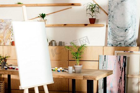 艺术家演播室内部与画架和桌与绘画供应和盆栽植物 