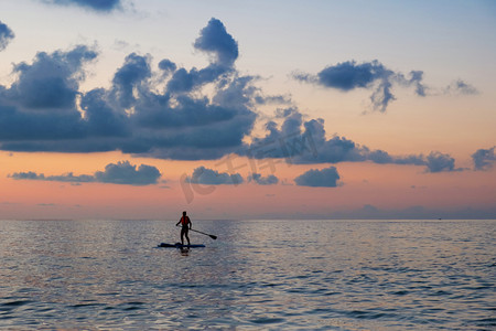 一个女孩剪影在桨板, 多云日落天空背景