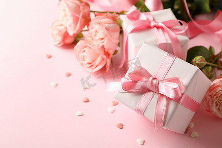 粉色礼品盒摄影照片_粉色背景的玫瑰和礼品盒，文字空间