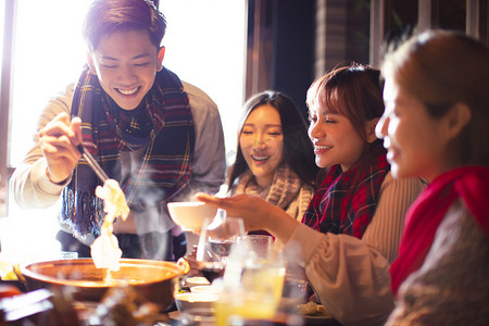 快乐的年轻朋友在冬天在餐馆吃火锅