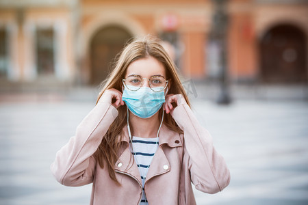 年轻女子戴上医疗口罩，以保护自己不受污染、感染和感染