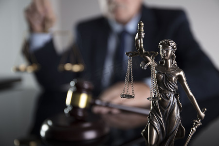 legal摄影照片_咨询律师的概念。办公室的律师在玻璃桌上的正义雕像, 槌和文件.