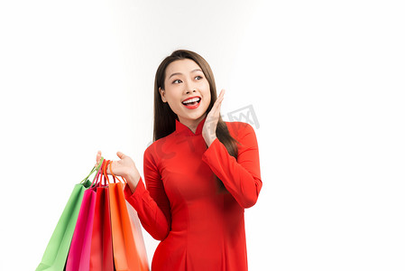 过年了过年了摄影照片_身着红衣的亚洲女士，提着白色背景的购物袋，过年快乐