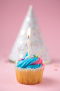粉色背景的生日纸杯蛋糕和帽子