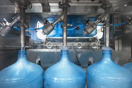 饮用水生产线。工业自动化机器，用于用饮用水填充塑料瓶或加仑，特写