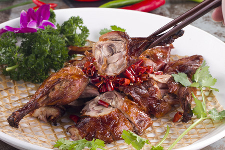 delicious摄影照片_Roast pigeon with dry red pepper in a white dish
