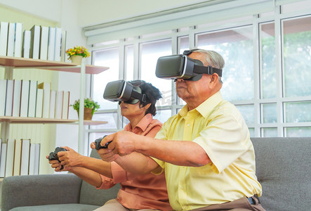 senior摄影照片_Senior Asian couple is playing Video game and wearing VR goggles for retirement technology lifestyle concept.