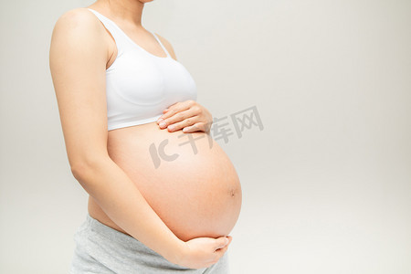 大肚子摄影照片_怀孕的女人摸她的大肚子。靠近点母亲、怀孕、人和期望的概念。怀孕妇女怀孕分娩