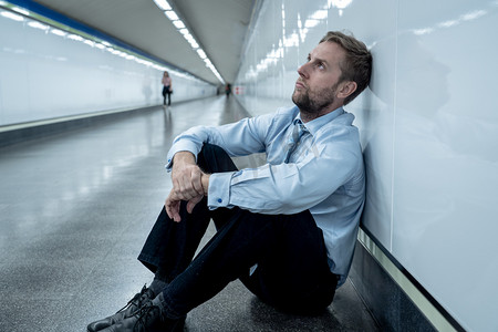 绝望的悲伤年轻的生意人遭受情感痛苦悲痛和深抑郁症独自坐在隧道地铁压力生活作风工作问题失败失业心理健康与抑郁症.