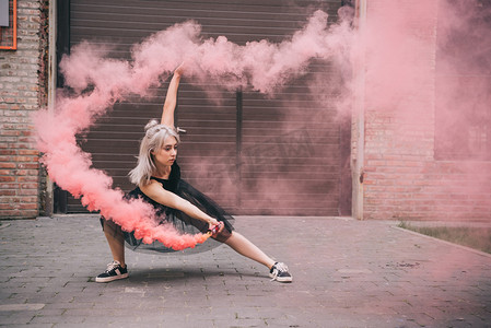 跳舞烟雾摄影照片_在城市街道粉红色烟雾跳舞的年轻妇女 