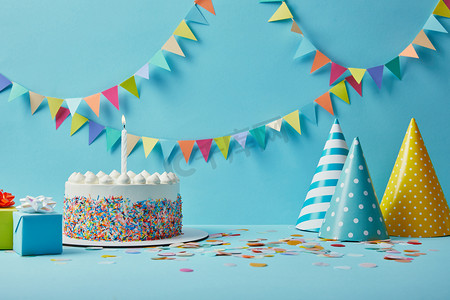 六一彩带简笔摄影照片_美味的生日蛋糕, 礼物, 派对帽和五彩纸屑蓝色背景与彩带