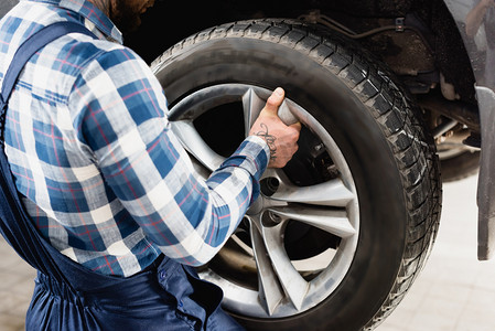 workshop摄影照片_partial view of technician fixing car wheel in workshop