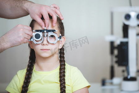 眼科医生为一名穿着黄色T恤、有辫子的少女测试眼镜框的眼科检查.