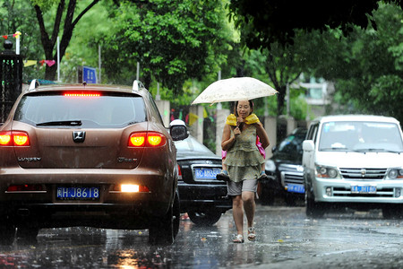 2013年9月13日，中国上海，一名妇女在一场大雨后，在被洪水淹没的街道上行走时抱着一个孩子。