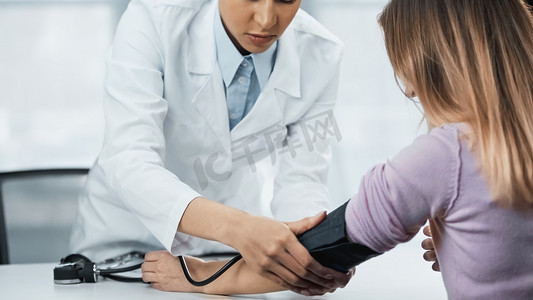 穿着白衣的非洲裔美国医生临床测量女性血压的剪影