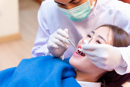 亚洲牙医摄影照片_牙科和牙齿保健。亚洲病人的牙科医生检查牙齿。医生的生活方式和在牙科诊所工作.