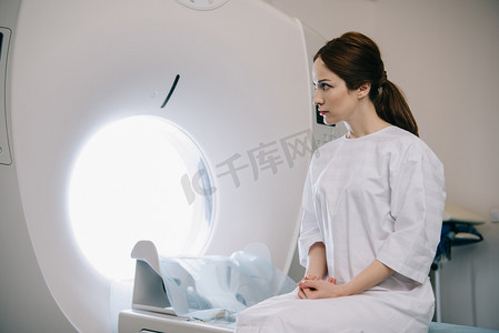 有吸引力的女人坐在计算机断层扫描床在医院