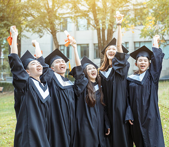 happy摄影照片_happy  students in graduation gowns holding diplomas on university campus