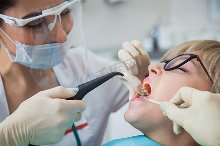 牙齿预防摄影照片_戴防护面罩的牙科医生用牙刷刷牙