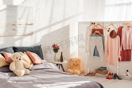 现代室内设计的卧室与泰迪熊玩具, 枕头, 衣架和床上的衣服