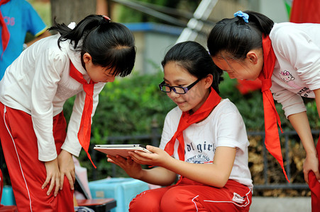 戴眼镜的学生摄影照片_9月 2 9日, 在中国西北甘肃省兰州市一所小学的课间休息时, 一名戴眼镜的年轻中国近视眼女生在她的 ipad 平板电脑上玩着一个手机游戏