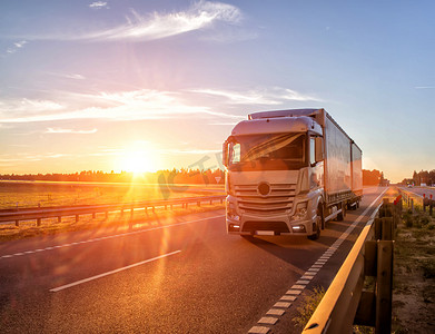 Modern wagon truck transports cargo against the backdrop of a sunset. The concept of truck drivers in the field of freight and logistics, copy space