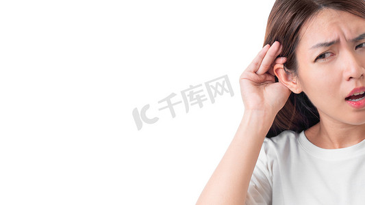 亚洲妇女身穿白色T恤，听力丧失或听力困难，手插在耳朵后面，因为她的背景是白色的，聋人的概念.
