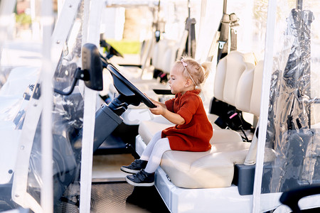 year摄影照片_Cute 2-year old is sitting in the drivers seat of a golf cart