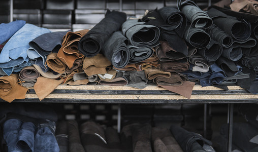 不同的皮革在一个卷。有色皮革的碎片。天然棕色和黑色和其他皮革的卷。生产箱包、鞋类、服装及配饰的原材料.